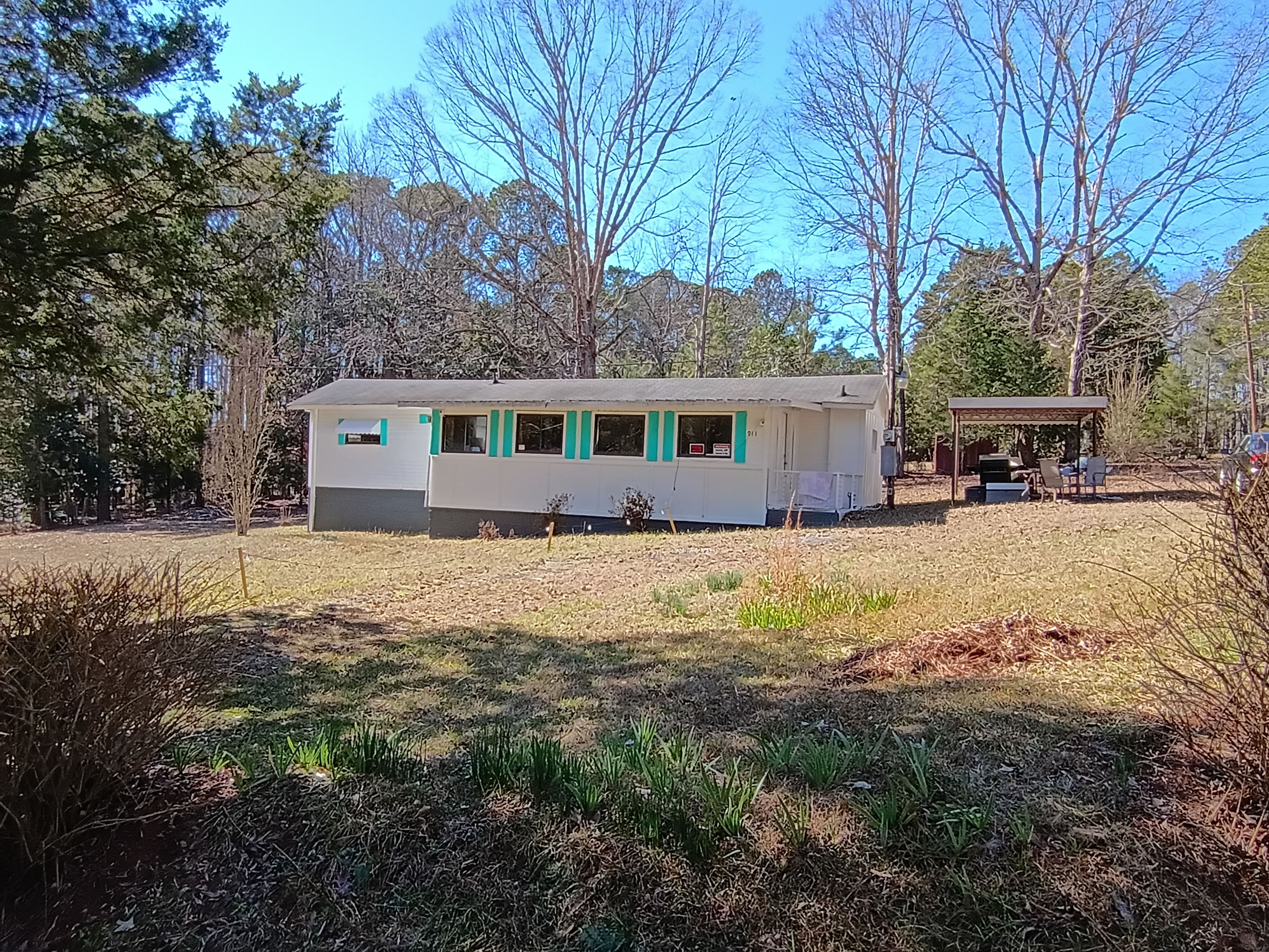 Double lot (owned land NO Site rent / NO HOA) with an older single wide mobile home with enclosed sunroom and carport